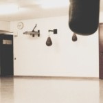 Vue panoramique de la salle d'entraînement du Boxing Club Nyon avec ses sacs de frappe et le logo du club au mur