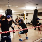 Plusieurs boxeurs travaillent simultanément aux sacs de frappe dans la salle du club